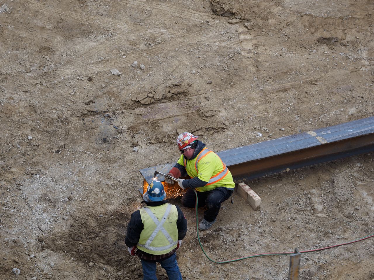 services-01 Two construction workers welding steel beams at a construction site.