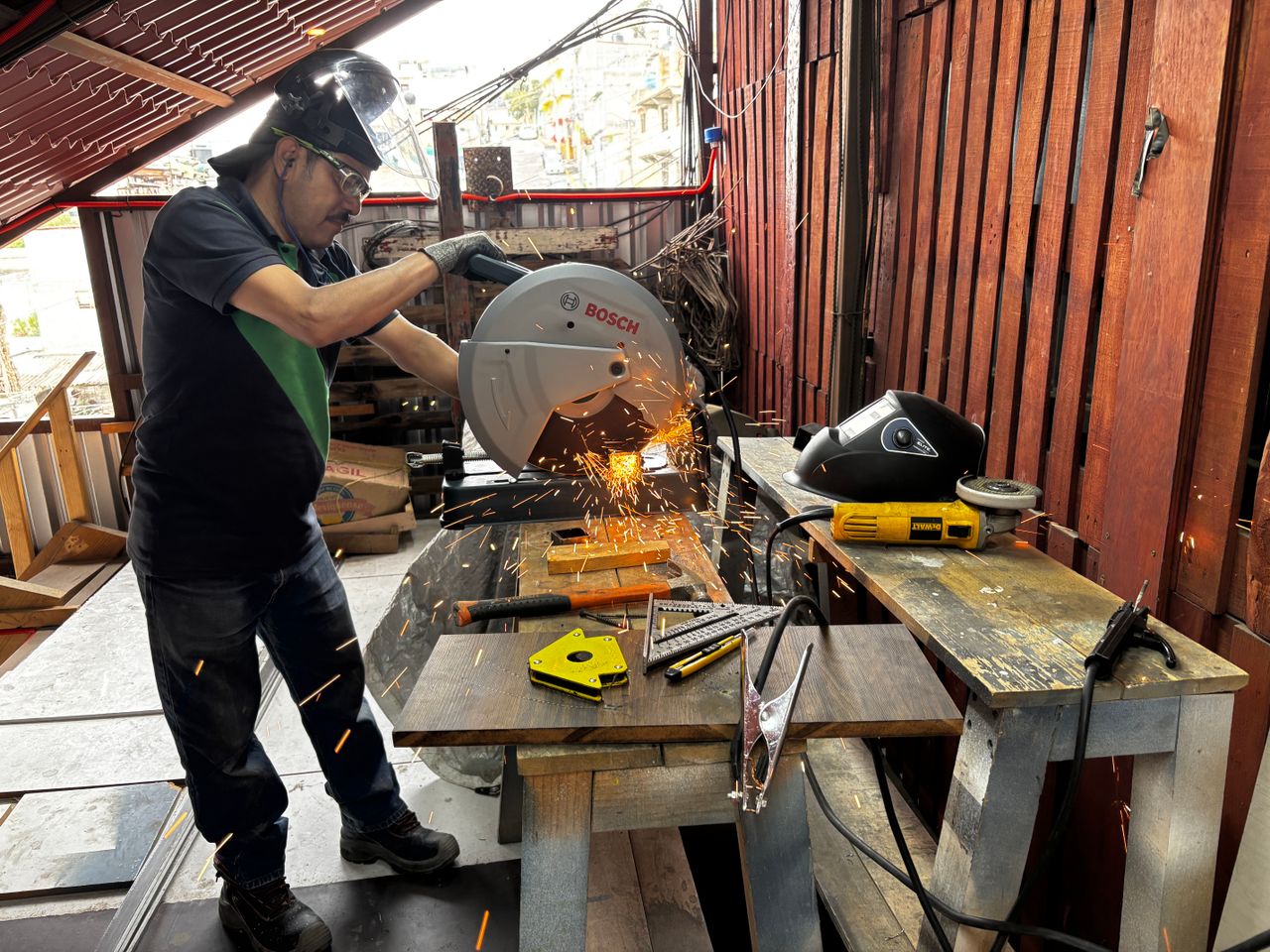 services-02 A man cuts metal with a saw in a workshop, creating vibrant sparks.