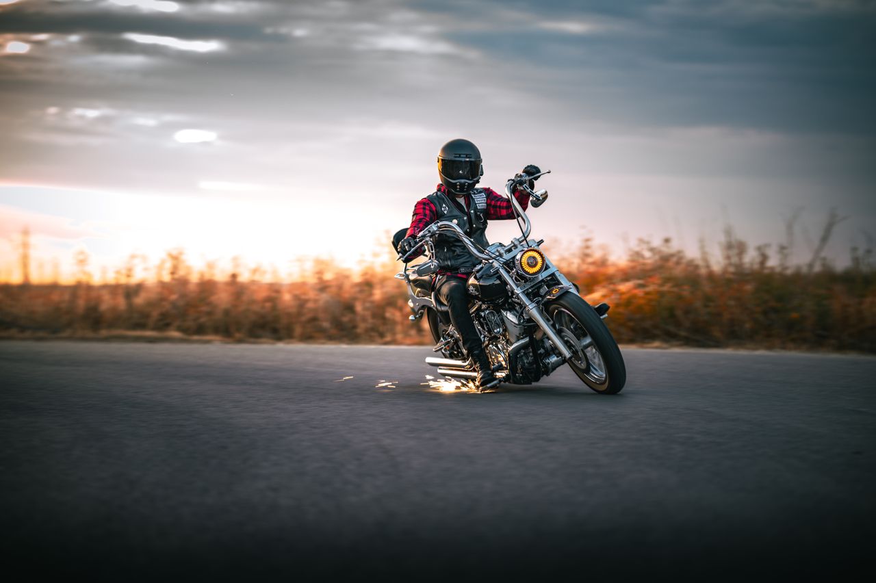journey-02 Motorcyclist in black helmet leans mid-turn on open road at sunset.